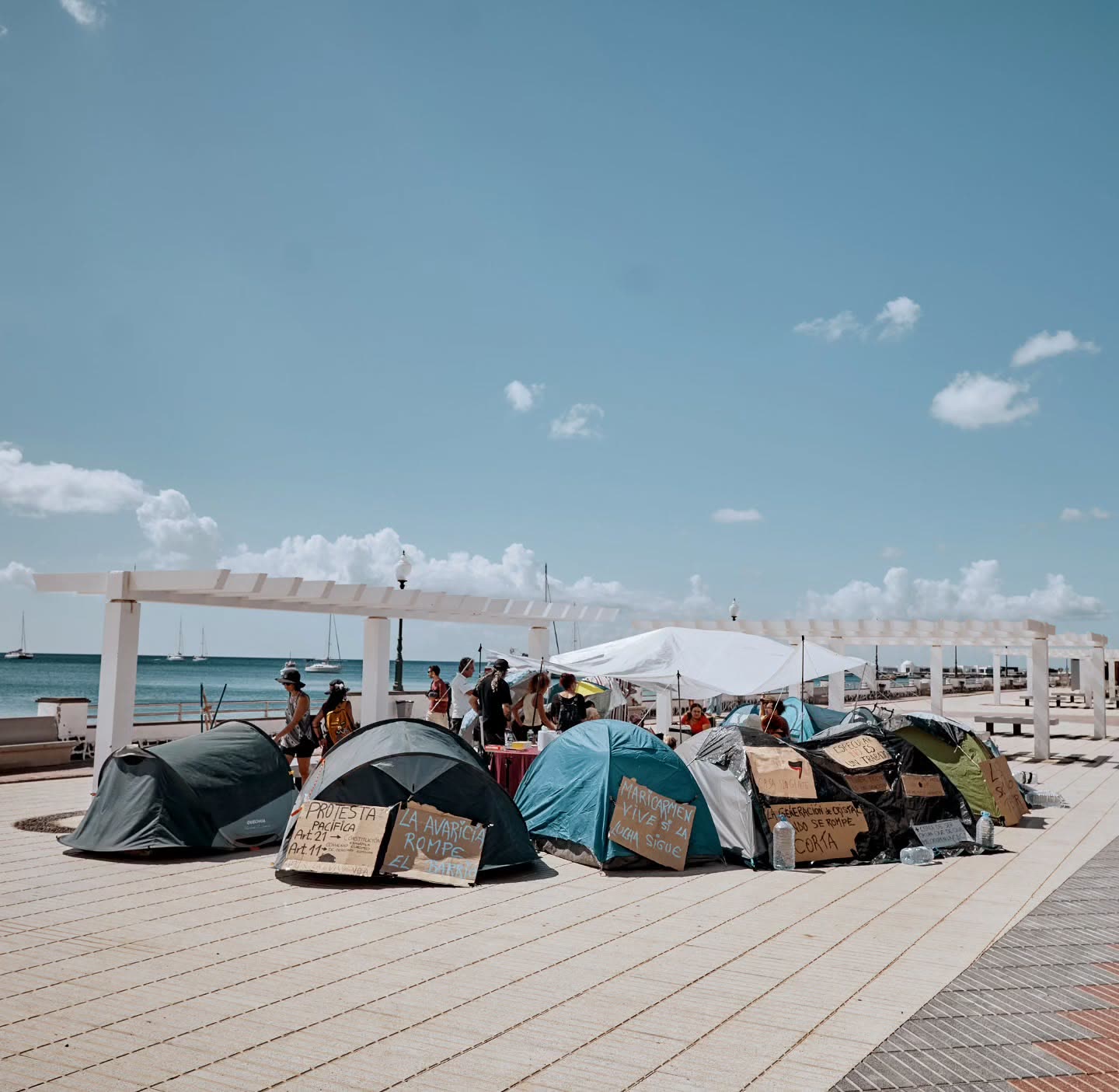 La acampada en la pérgola del parque, con el mar y los veleros detrás