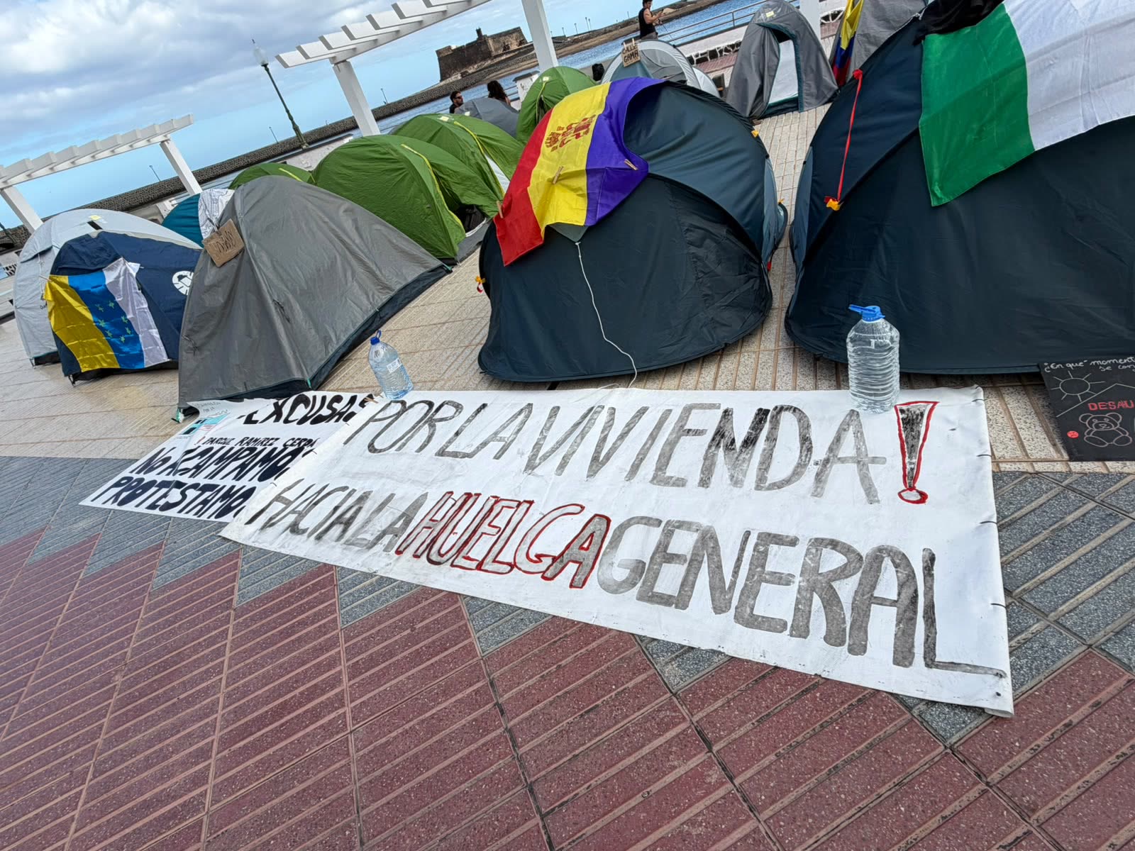 Tiendas de campaña y la pancarta «¡Por la vivienda! Hacia la huelga general»